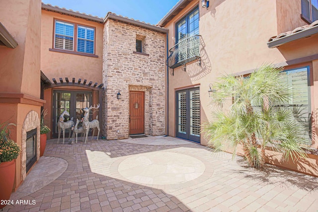 view of patio / terrace featuring a balcony, french doors, and a glass covered fireplace