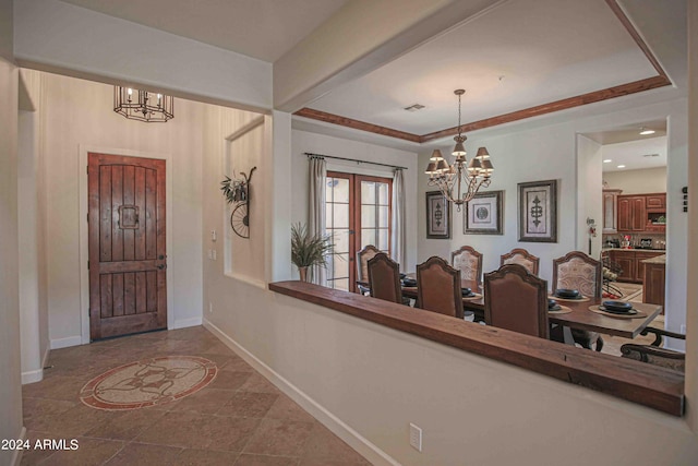 entryway with an inviting chandelier, a tray ceiling, baseboards, and visible vents