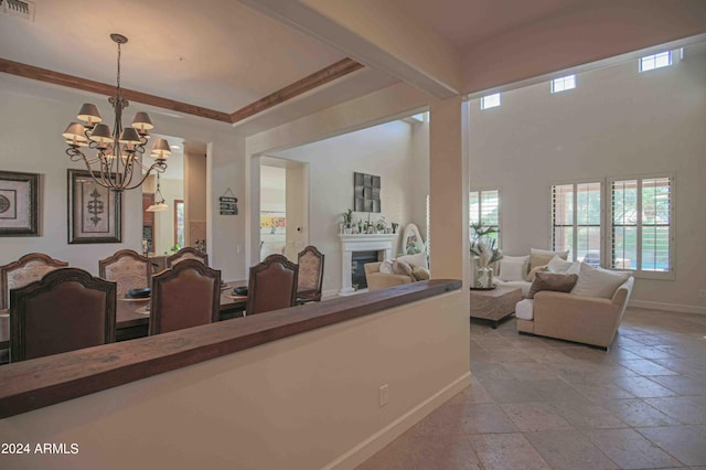 interior space with a fireplace, stone tile flooring, baseboards, visible vents, and an inviting chandelier