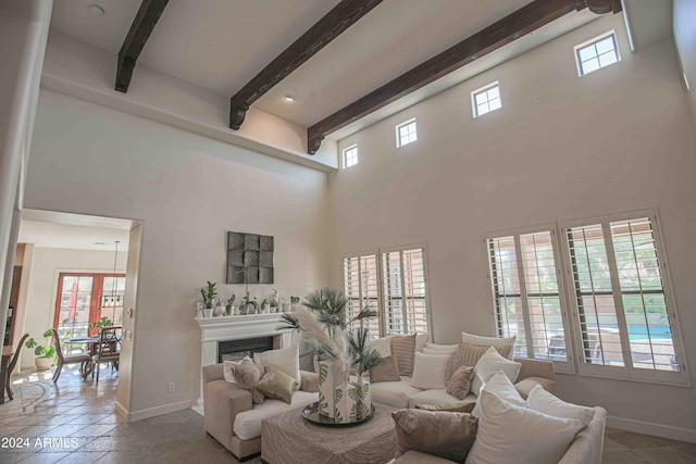 living room featuring a towering ceiling, beam ceiling, baseboards, and a fireplace