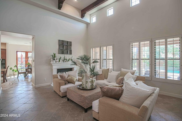 living room with baseboards, a towering ceiling, stone tile flooring, and beamed ceiling