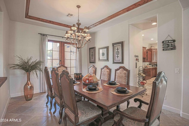 dining room featuring an inviting chandelier, a tray ceiling, baseboards, and visible vents