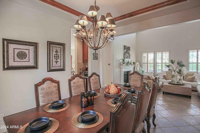 dining area with a fireplace, a chandelier, stone tile flooring, and beam ceiling