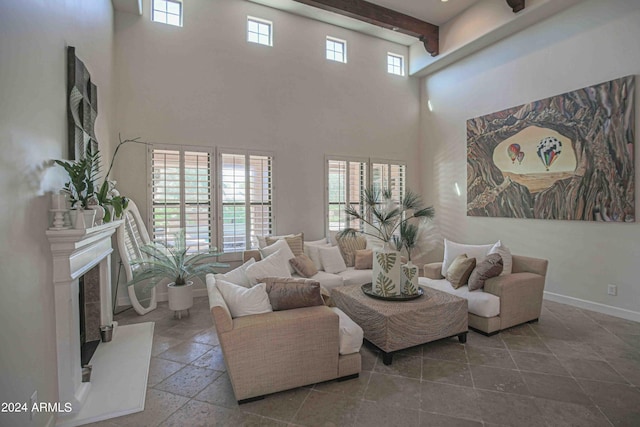 living area featuring baseboards, a high end fireplace, a towering ceiling, and a healthy amount of sunlight