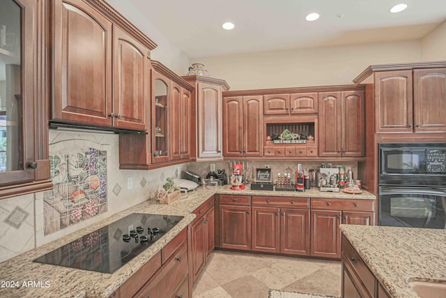 kitchen featuring light stone counters, tasteful backsplash, glass insert cabinets, black appliances, and recessed lighting