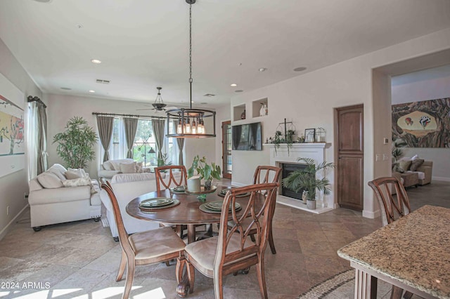 dining area with a ceiling fan, a fireplace with raised hearth, baseboards, visible vents, and recessed lighting