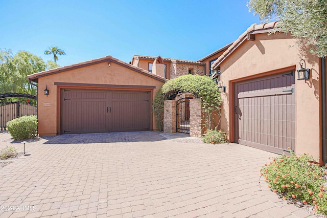view of front of house with stucco siding, a gate, a garage, and decorative driveway