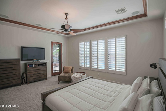 bedroom featuring a ceiling fan, a tray ceiling, carpet, and visible vents