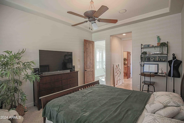 bedroom featuring a tray ceiling, baseboards, and ceiling fan