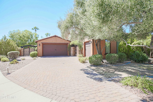 view of front facade with a gate, decorative driveway, stucco siding, and fence