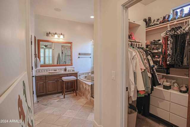 bathroom featuring a spacious closet, tile patterned floors, vanity, and a bath