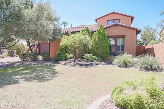 mediterranean / spanish home featuring stucco siding, a tile roof, fence, and a front yard