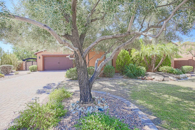 view of yard with decorative driveway, fence, and a garage