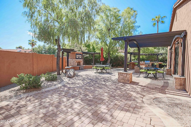 view of patio / terrace featuring an outdoor stone fireplace, fence, outdoor dining space, and a pergola