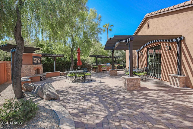 view of patio featuring a pergola, outdoor dining area, and an outdoor stone fireplace