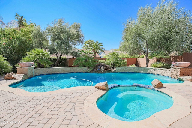 view of swimming pool featuring a fenced backyard, a pool with connected hot tub, and a patio