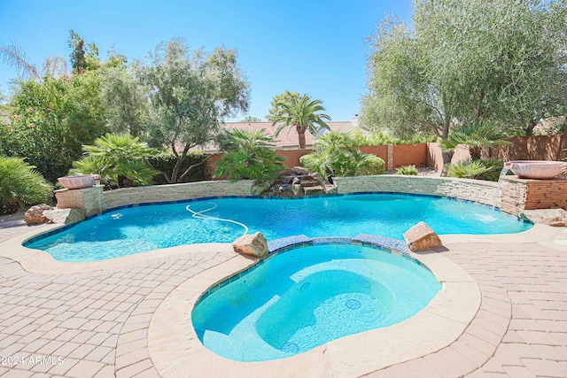 view of pool with a fenced backyard, a pool with connected hot tub, and a patio area