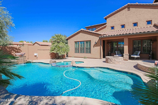 view of pool featuring fence, a pool with connected hot tub, an outdoor fire pit, and a patio