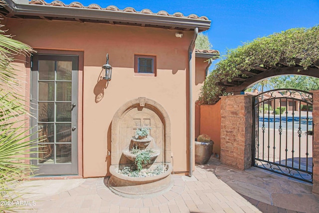 doorway to property featuring stucco siding, a gate, and a tiled roof