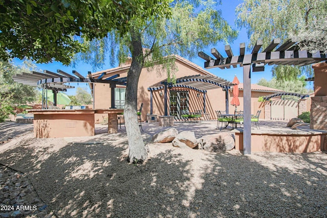 view of front of property with outdoor dry bar, a pergola, stucco siding, and a patio area