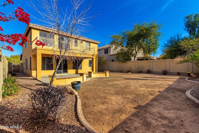 rear view of house featuring a balcony and a patio