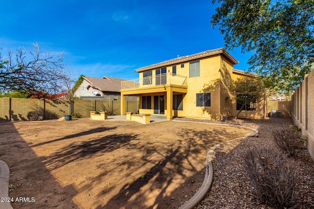 back of property with a balcony, central air condition unit, and a patio