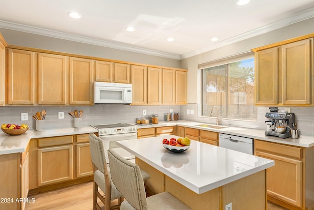 kitchen featuring a breakfast bar area, a center island, white appliances, and sink