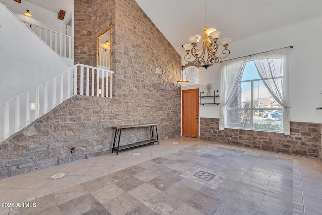 unfurnished living room featuring high vaulted ceiling, stairway, and an inviting chandelier