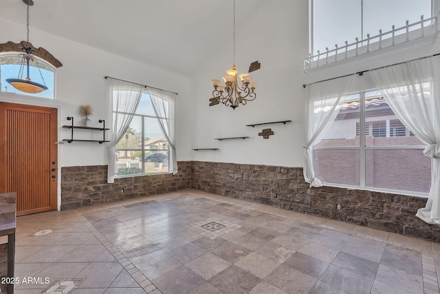 entrance foyer featuring a wainscoted wall, a towering ceiling, and an inviting chandelier