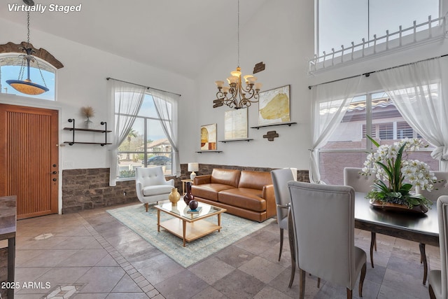 living area featuring wainscoting, a notable chandelier, and a towering ceiling