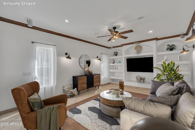 living room with light tile patterned floors, built in shelves, a ceiling fan, and crown molding