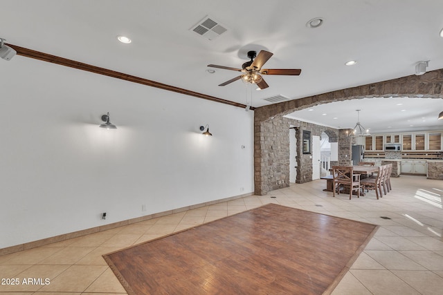 unfurnished dining area with light tile patterned floors, ornamental molding, ceiling fan with notable chandelier, and visible vents