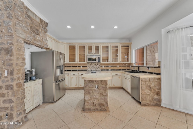 kitchen with a center island, light countertops, glass insert cabinets, appliances with stainless steel finishes, and a sink