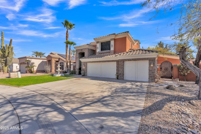 mediterranean / spanish-style home featuring an attached garage, a tile roof, stone siding, concrete driveway, and stucco siding