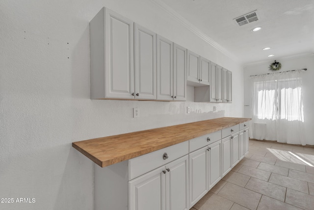 kitchen featuring visible vents, wooden counters, and white cabinetry