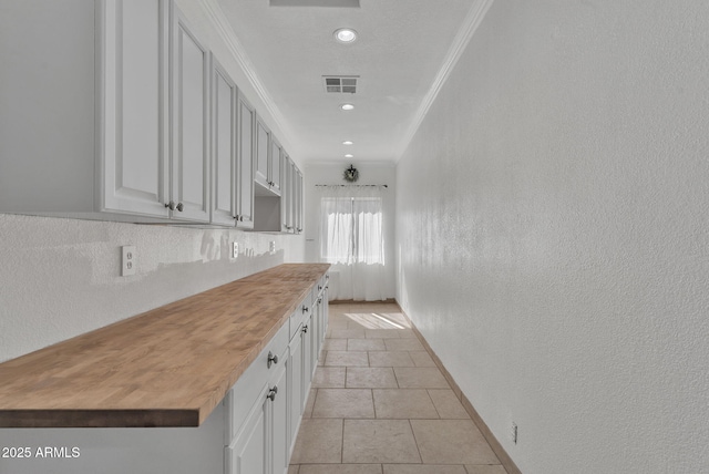 kitchen featuring crown molding, butcher block counters, visible vents, and white cabinets