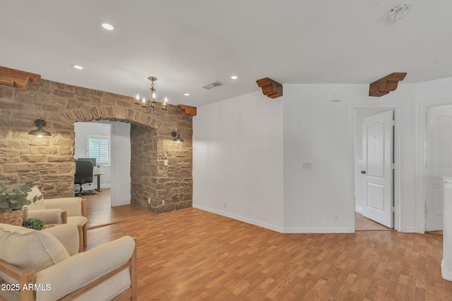 living area with arched walkways, recessed lighting, visible vents, light wood-style floors, and baseboards