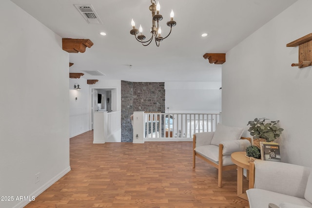 living area with light wood-style floors, recessed lighting, visible vents, and an inviting chandelier