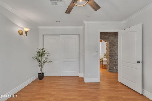 unfurnished bedroom with crown molding, a closet, visible vents, light wood-type flooring, and baseboards