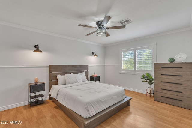 bedroom featuring baseboards, ornamental molding, visible vents, and light wood-style floors