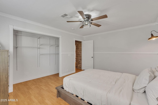 bedroom with visible vents, light wood-style flooring, ceiling fan, crown molding, and a closet