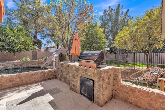 view of patio featuring exterior kitchen, a fenced backyard, and a grill