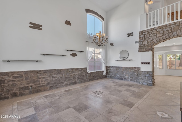 interior space featuring wainscoting, a healthy amount of sunlight, a towering ceiling, and an inviting chandelier