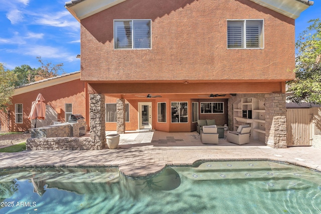 back of house featuring a fenced in pool, a fireplace, a patio, ceiling fan, and stone siding