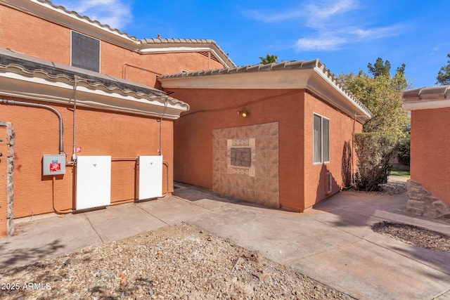 view of property exterior with a tiled roof, a patio area, and stucco siding