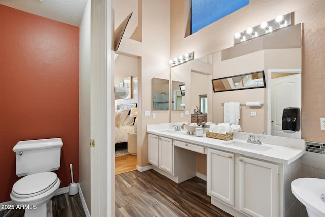 bathroom featuring hardwood / wood-style floors, vanity, toilet, and a washtub