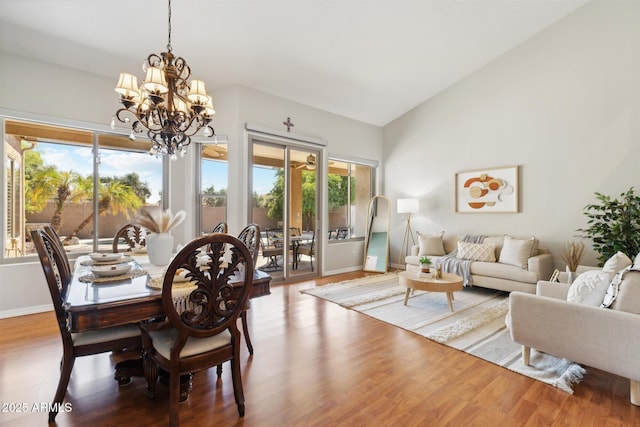 dining area with wood-type flooring, lofted ceiling, and a notable chandelier