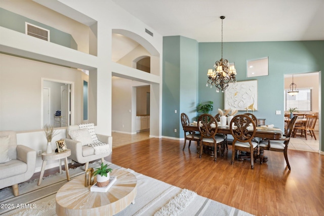 dining space featuring a notable chandelier, wood-type flooring, and a high ceiling