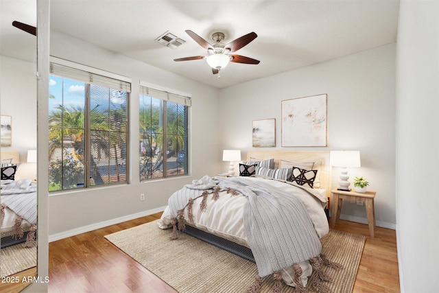 bedroom featuring ceiling fan, wood-type flooring, and multiple windows