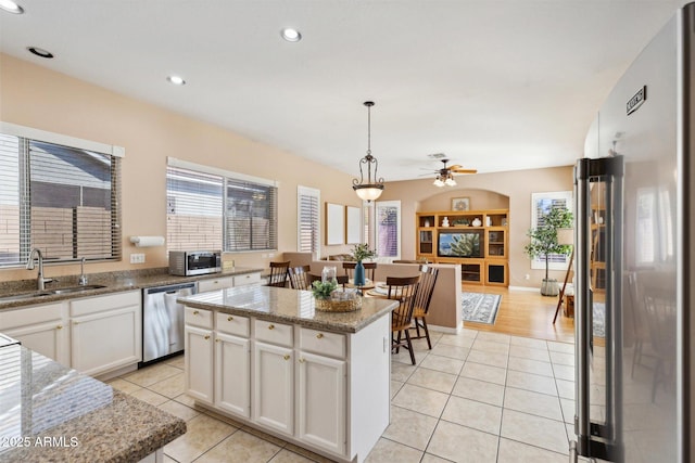 kitchen featuring appliances with stainless steel finishes, sink, decorative light fixtures, white cabinets, and a kitchen island